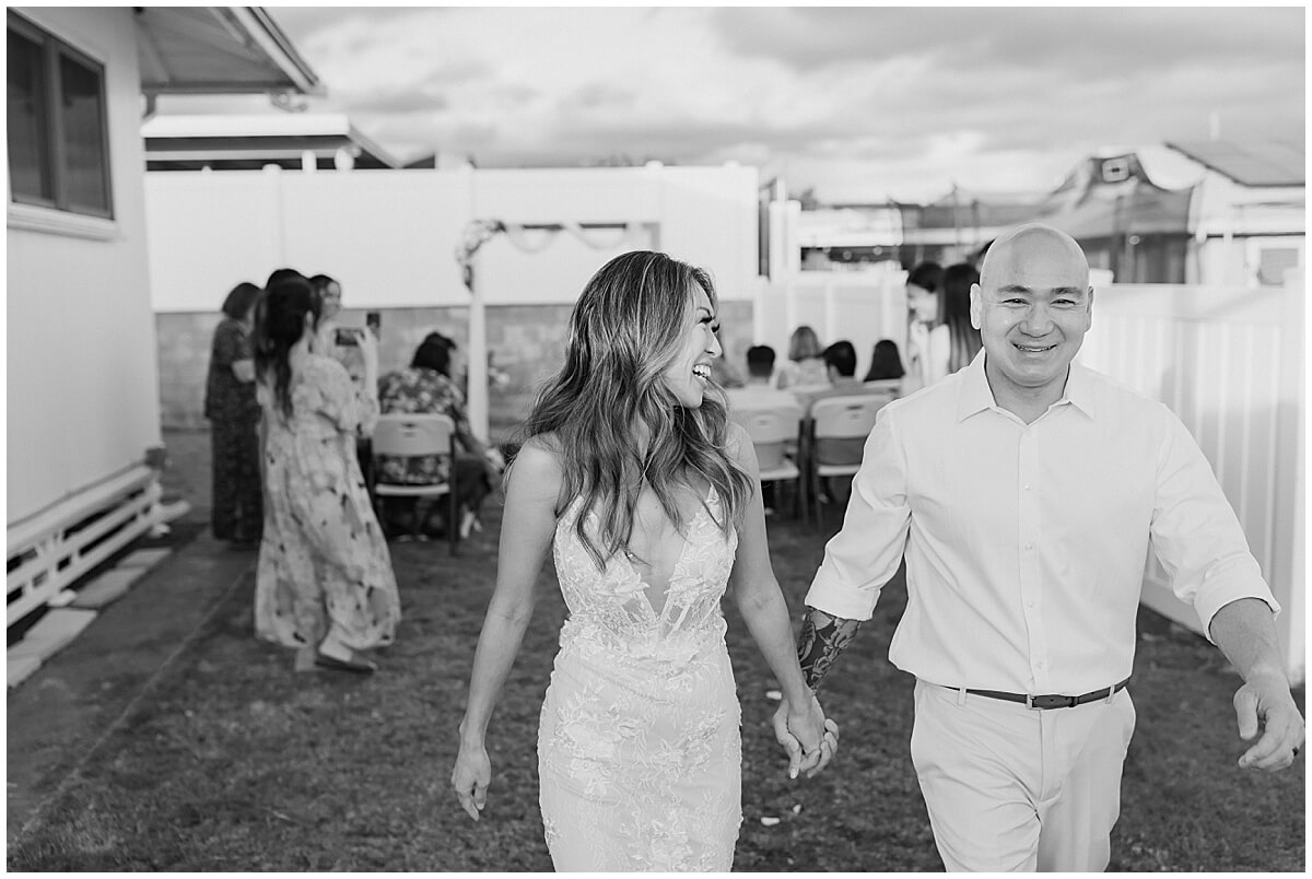 newly married bride and groom walk back up the aisle for pearl city backyard celebration